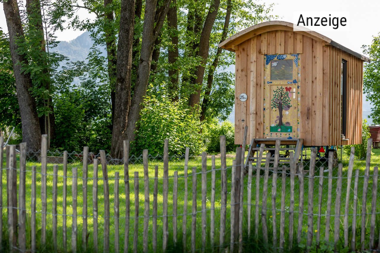 Bauwagen des Montessori-Kindergartens auf grüner Wiese in der Wohnanlage Dahoam im Inntal